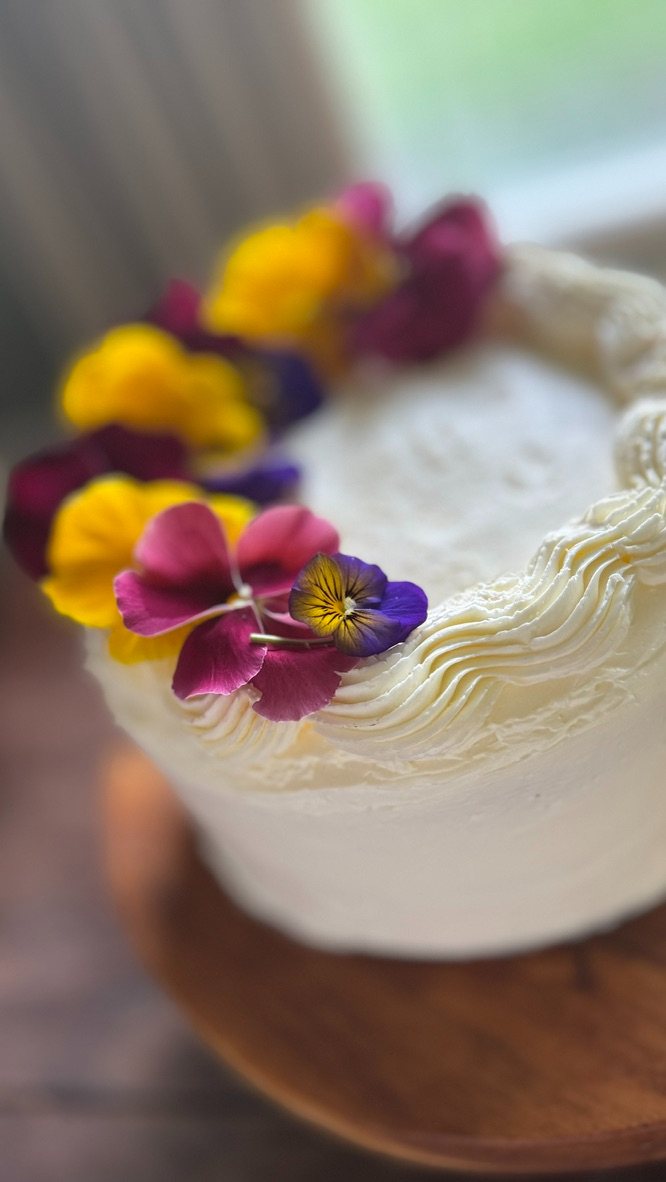A white cake topped with edible pansies