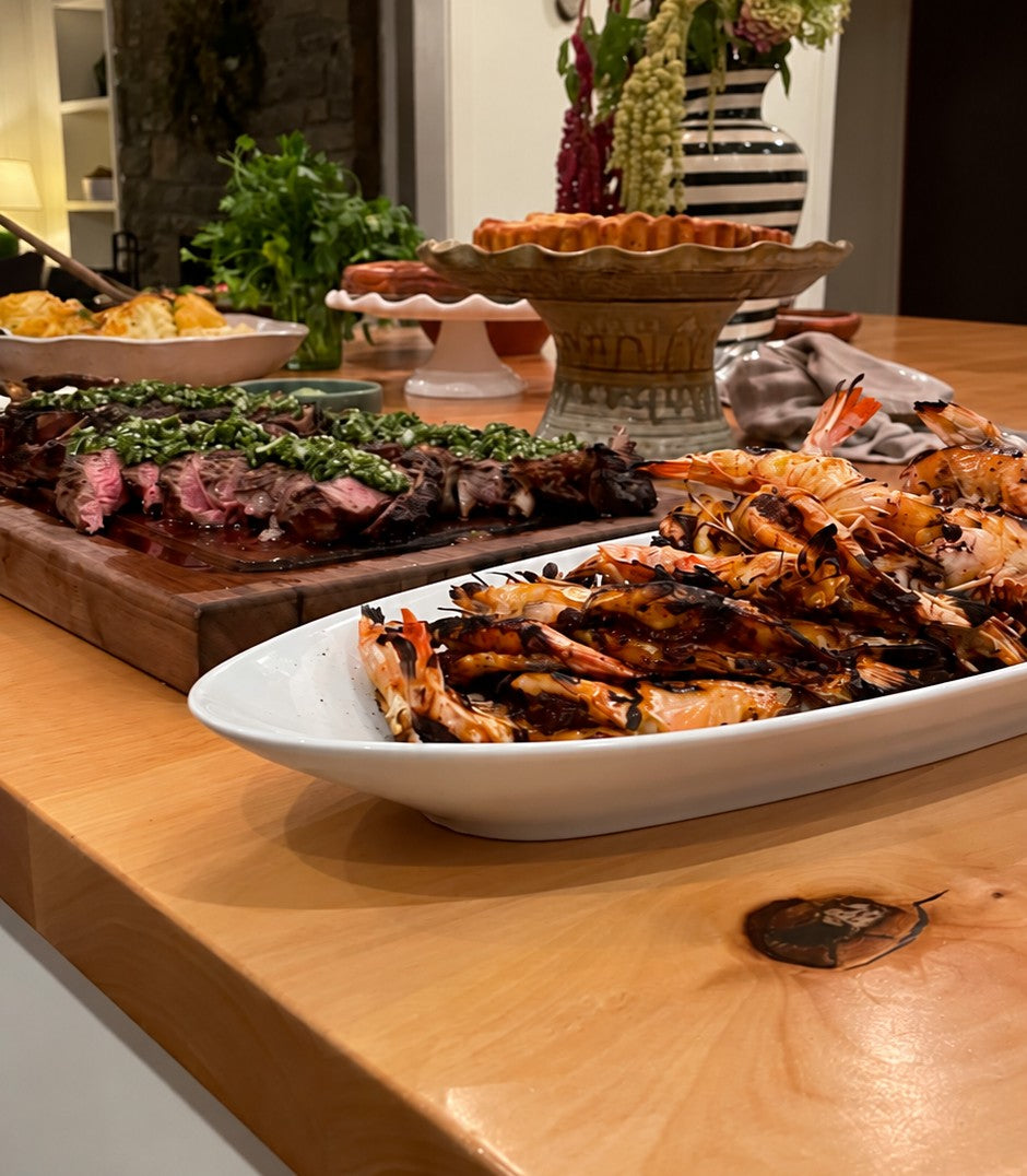 Steak with chimichurri and grilled shrimp set out on a buffet