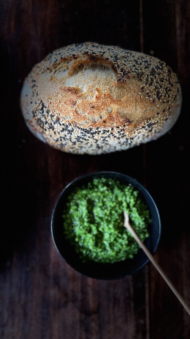 Sesame sourdough loaf with a bowl of green herb salt