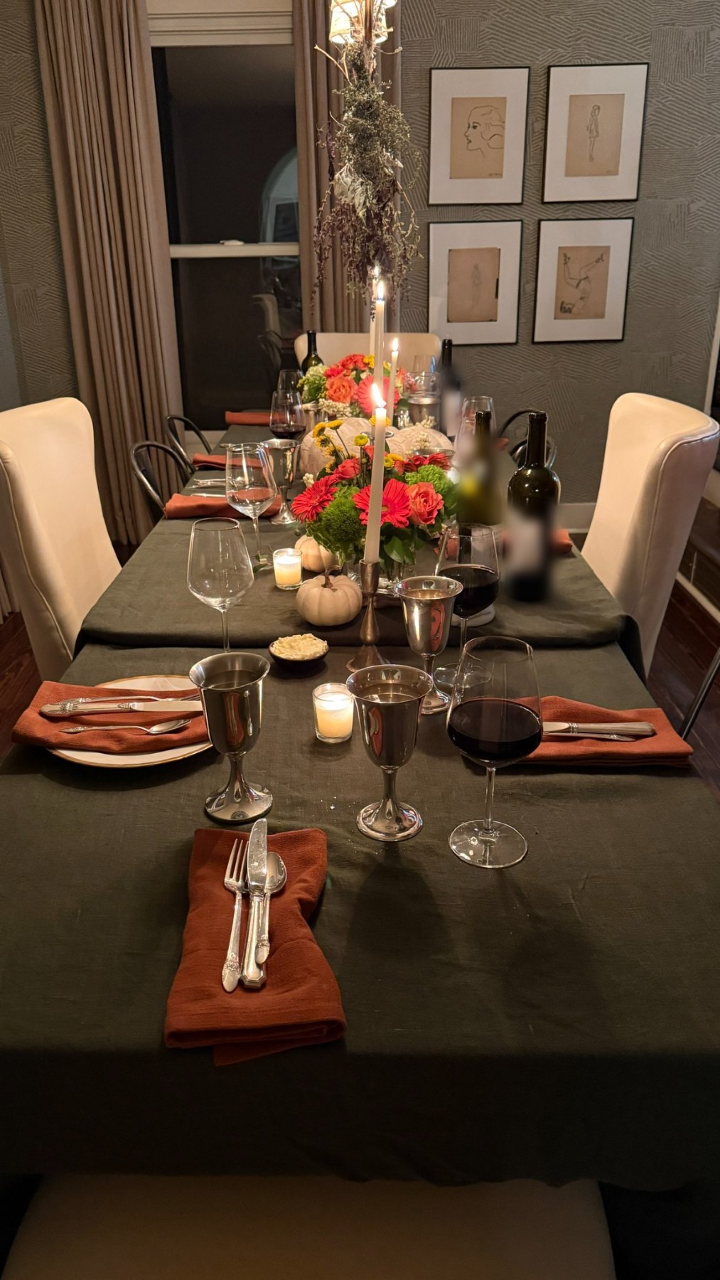 A candlelit dinner party table set with linen, flowers, and silver goblets