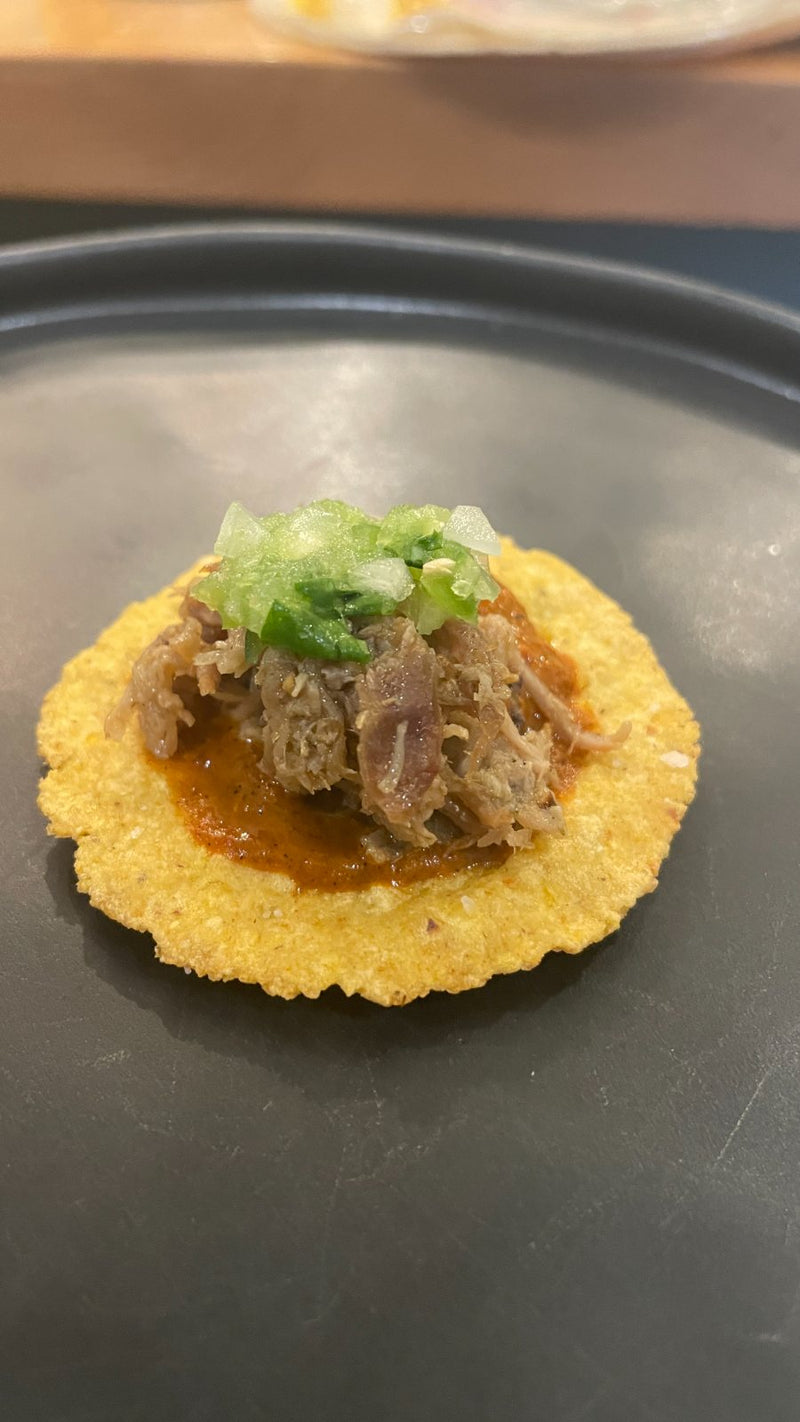A pork tostada bite with salsa verde